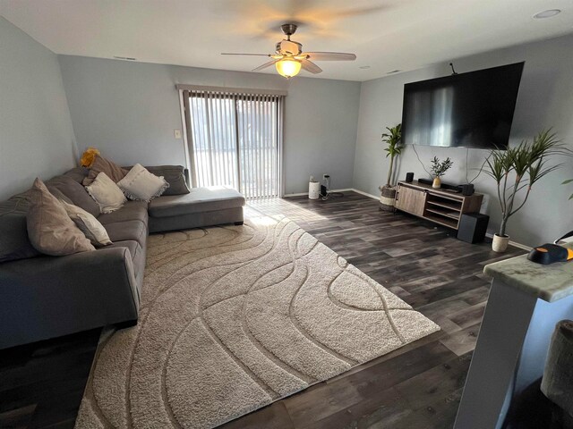 living room featuring dark wood-type flooring and ceiling fan