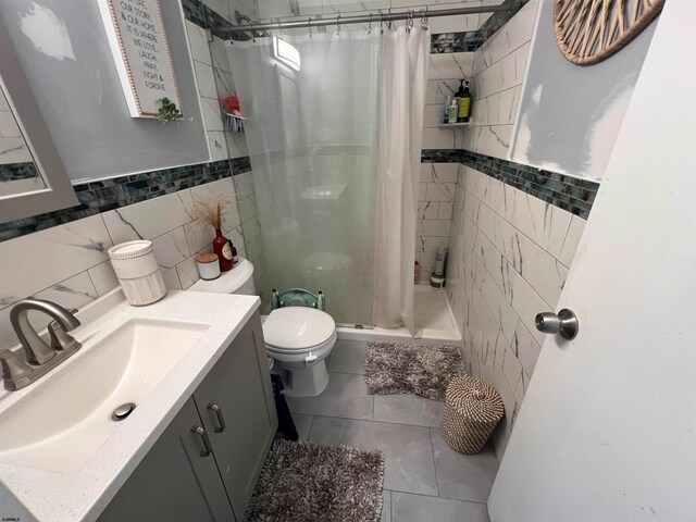 bathroom featuring tile patterned floors, toilet, tile walls, vanity, and a shower with shower curtain