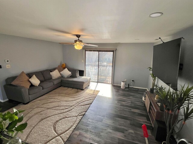 living room featuring dark wood-type flooring and ceiling fan