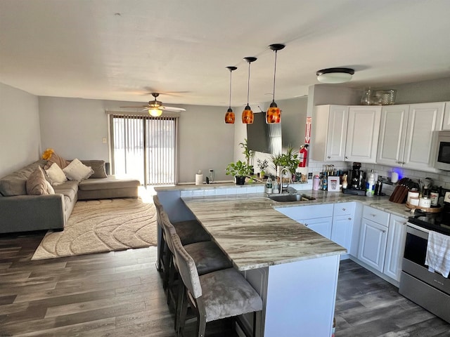 kitchen with pendant lighting, sink, white cabinets, kitchen peninsula, and stainless steel appliances