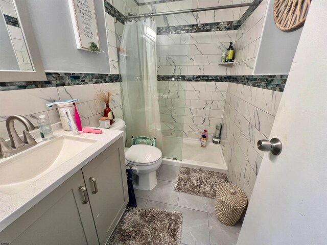 bathroom featuring tile walls, a shower with shower curtain, vanity, tile patterned floors, and toilet