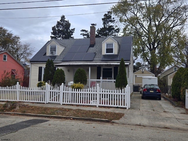 new england style home featuring an outdoor structure, covered porch, a garage, and solar panels