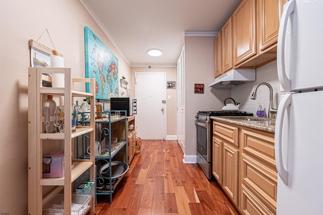 kitchen featuring stainless steel gas range, light hardwood / wood-style flooring, white refrigerator, backsplash, and crown molding