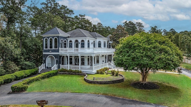 view of front of home featuring covered porch, a balcony, and a front lawn