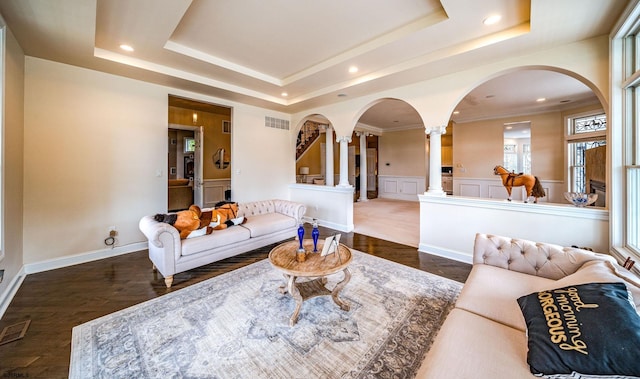 living room featuring decorative columns, dark hardwood / wood-style floors, and a tray ceiling