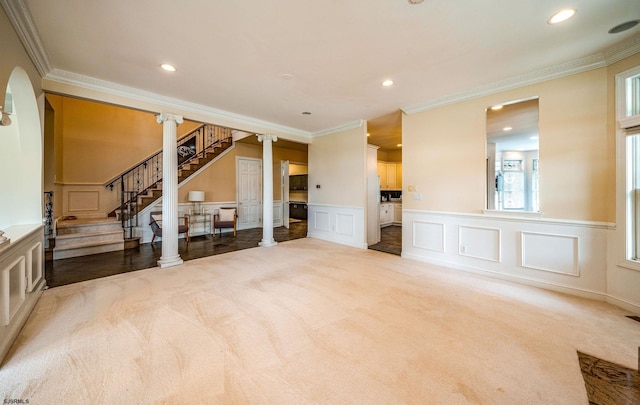 unfurnished living room with light colored carpet, crown molding, and decorative columns