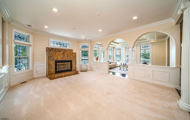 unfurnished living room with ornate columns, crown molding, and light carpet