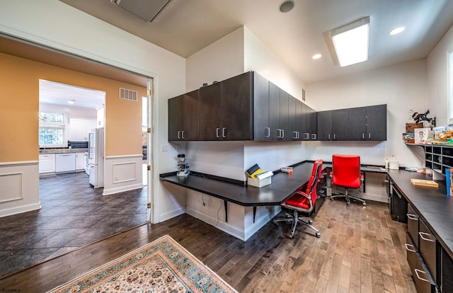 office with dark hardwood / wood-style flooring and built in desk