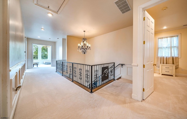 hall with light carpet, an inviting chandelier, and crown molding