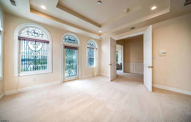 spare room featuring light carpet and a tray ceiling