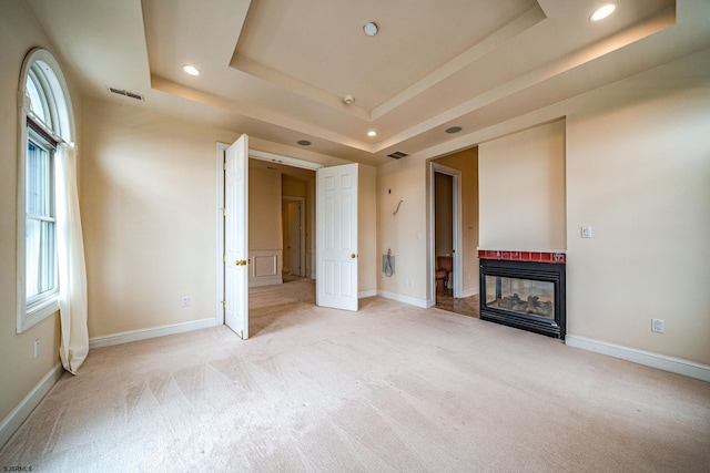 unfurnished living room with light colored carpet and a tray ceiling