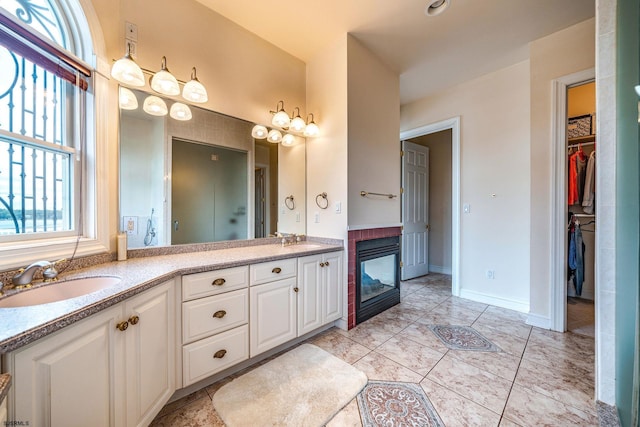 bathroom with a multi sided fireplace and vanity