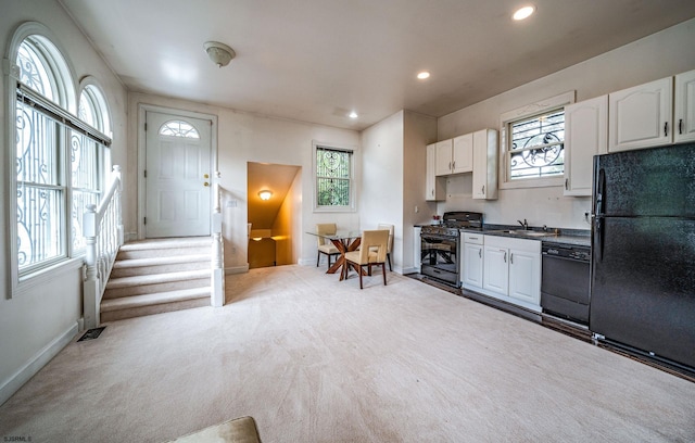 kitchen with black appliances, plenty of natural light, and white cabinetry