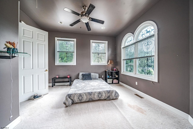 carpeted bedroom with ceiling fan and multiple windows