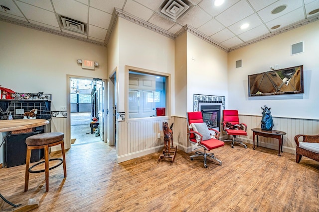 sitting room with hardwood / wood-style floors, a drop ceiling, a towering ceiling, and a fireplace