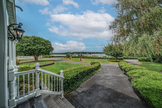 view of home's community with a water view and a lawn