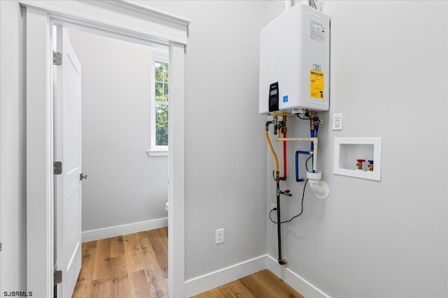 washroom with washer hookup, tankless water heater, and light wood-type flooring