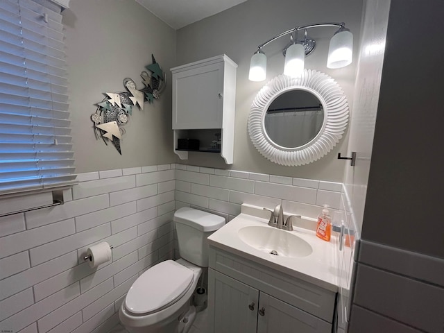 bathroom featuring vanity, toilet, and tile walls