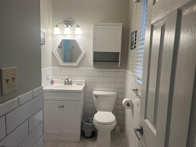 bathroom featuring tile patterned flooring, vanity, toilet, and tile walls