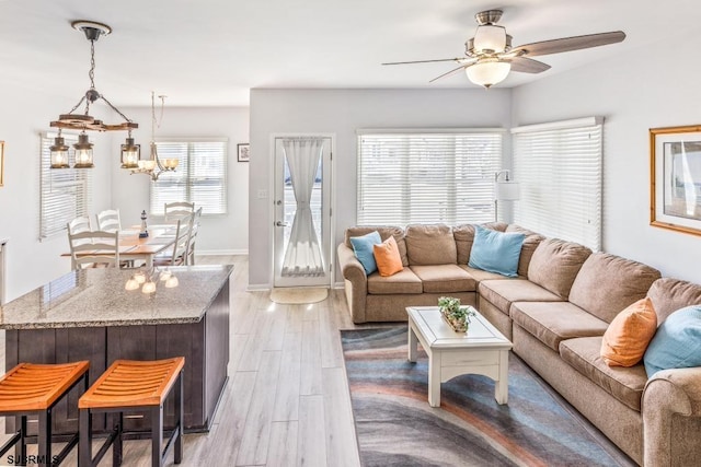 living room with light hardwood / wood-style flooring and ceiling fan with notable chandelier