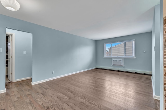 spare room featuring an AC wall unit, baseboard heating, and light hardwood / wood-style flooring