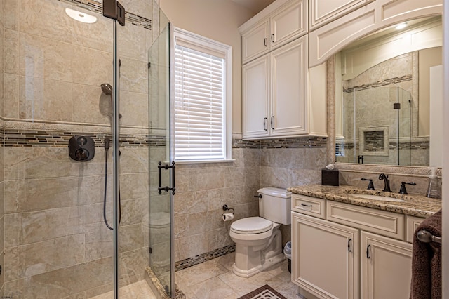 bathroom with vanity, toilet, walk in shower, and tile walls