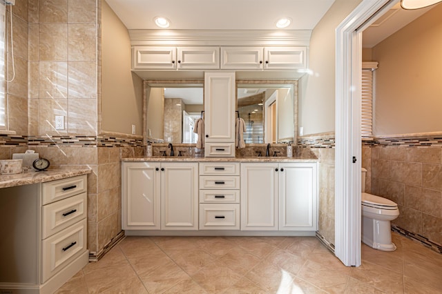 bathroom featuring tile patterned flooring, vanity, tile walls, and toilet