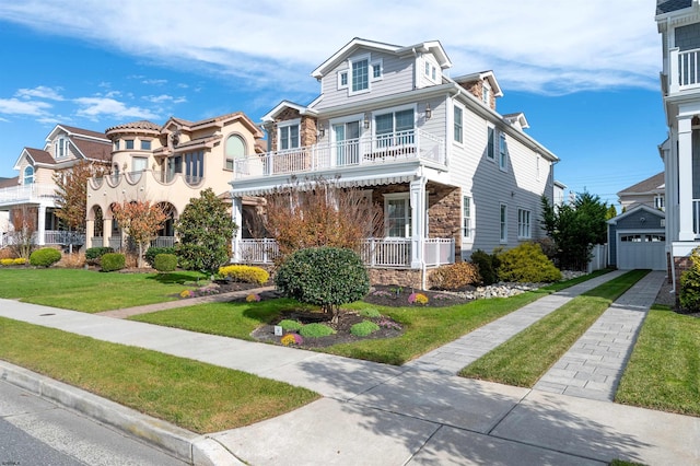 view of front of house with a garage, a balcony, an outbuilding, and a front lawn