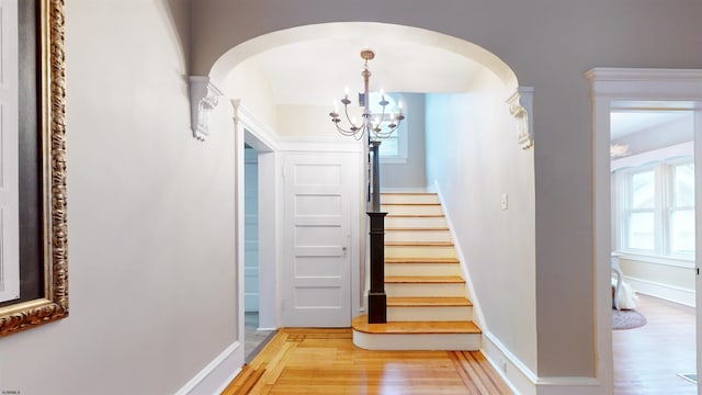 stairway with wood-type flooring and a chandelier