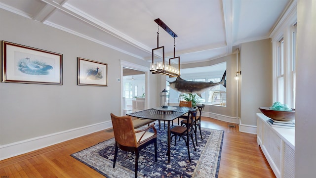 dining area featuring crown molding, beamed ceiling, a chandelier, and light wood-type flooring