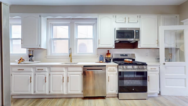 kitchen featuring white cabinets, light hardwood / wood-style floors, appliances with stainless steel finishes, and tasteful backsplash