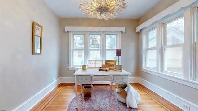 home office with a chandelier, a healthy amount of sunlight, and light hardwood / wood-style flooring