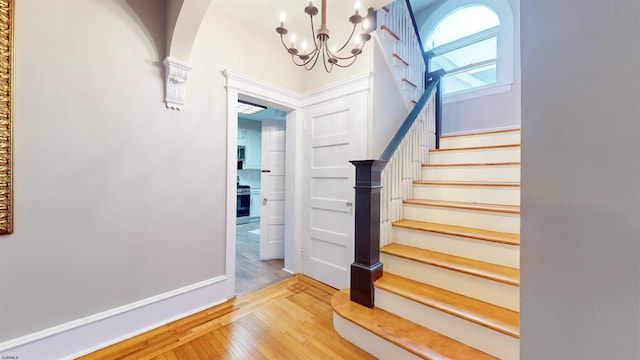 stairs featuring hardwood / wood-style flooring and a notable chandelier