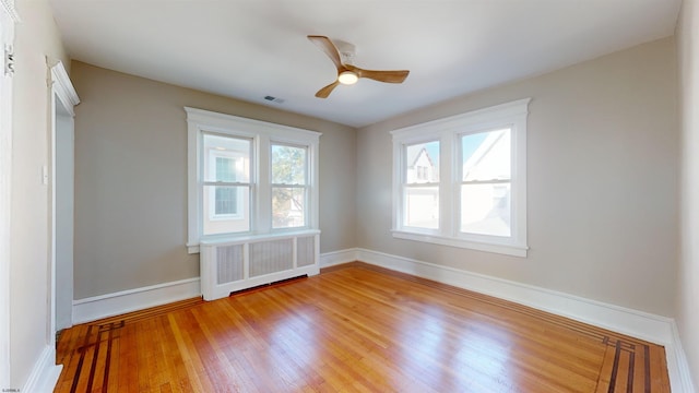 spare room with hardwood / wood-style flooring, radiator, and ceiling fan