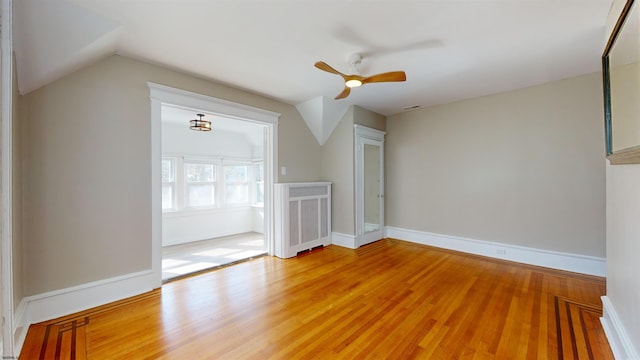 interior space featuring radiator, hardwood / wood-style flooring, vaulted ceiling, and ceiling fan