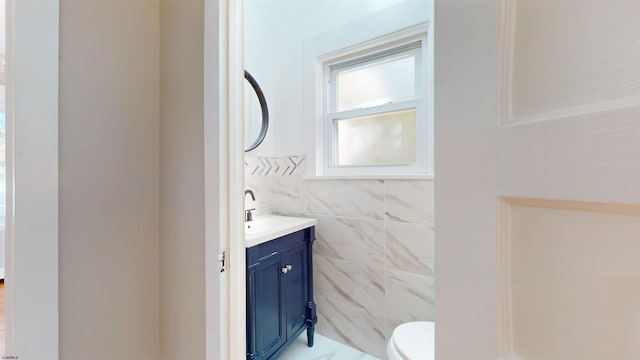 bathroom with vanity, tile walls, and toilet