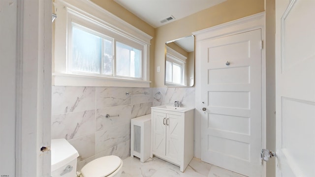 bathroom featuring vanity, tile walls, and toilet