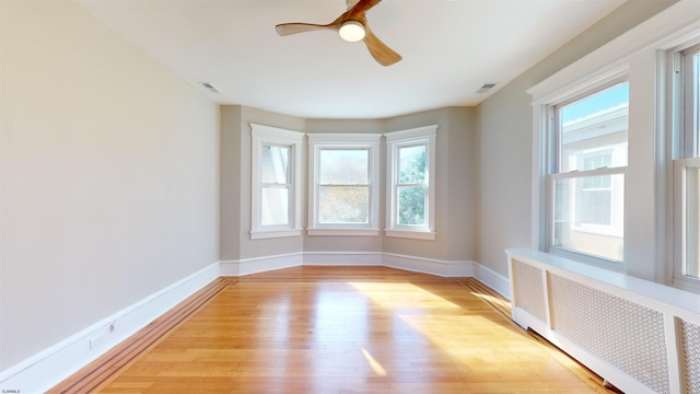 spare room featuring ceiling fan, radiator, and light hardwood / wood-style flooring