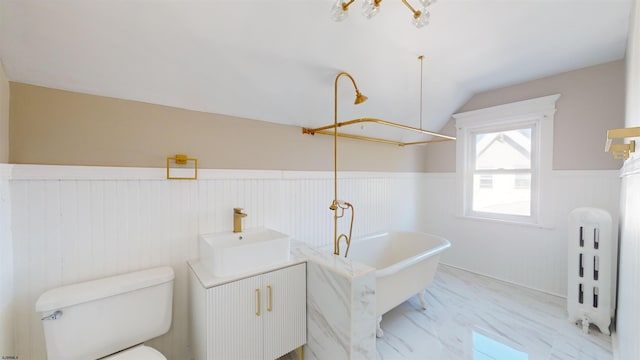 bathroom with a bathtub, vanity, lofted ceiling, and toilet