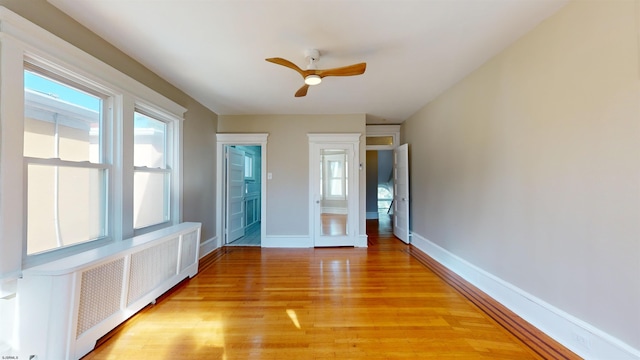 interior space featuring light wood-type flooring, radiator, and ceiling fan