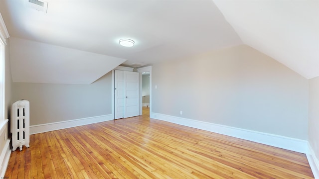 additional living space featuring light hardwood / wood-style flooring, radiator, and lofted ceiling