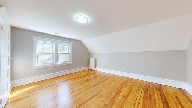 bonus room with lofted ceiling, light wood-type flooring, and radiator