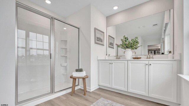 bathroom with vanity, a shower with shower door, and hardwood / wood-style floors