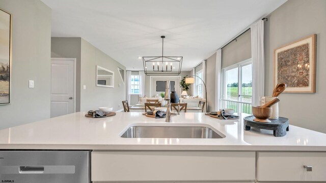 kitchen featuring pendant lighting, sink, dishwasher, and an inviting chandelier