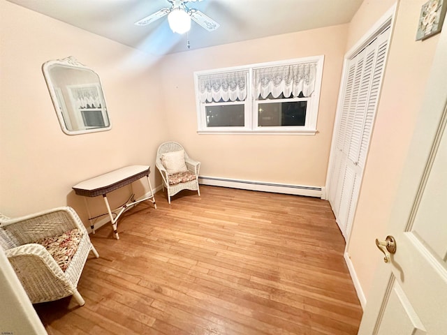 sitting room featuring ceiling fan, light hardwood / wood-style floors, and a baseboard heating unit