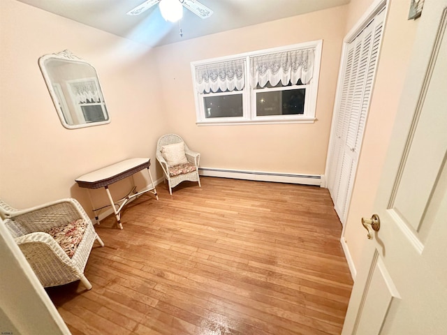 sitting room featuring a baseboard radiator, light hardwood / wood-style flooring, and ceiling fan