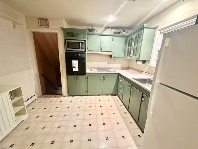 kitchen featuring white appliances, green cabinetry, a baseboard heating unit, and sink