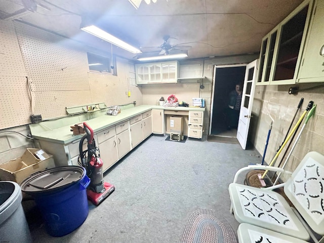 kitchen featuring concrete flooring, white cabinetry, and ceiling fan