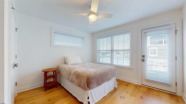 bedroom with access to outside, multiple windows, ceiling fan, and light hardwood / wood-style flooring