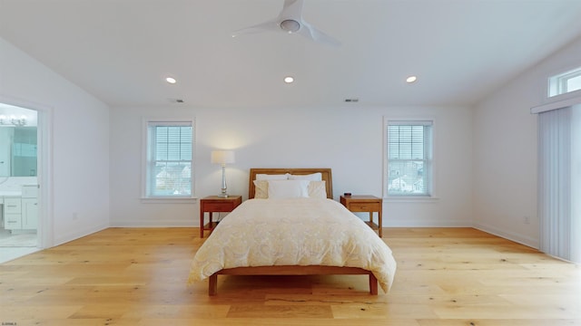 bedroom featuring light wood-type flooring, multiple windows, and ensuite bath